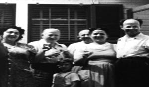 Black-and-white photo of five Eastern European Jewish adults and one child standing in a row and smiling for the camera.